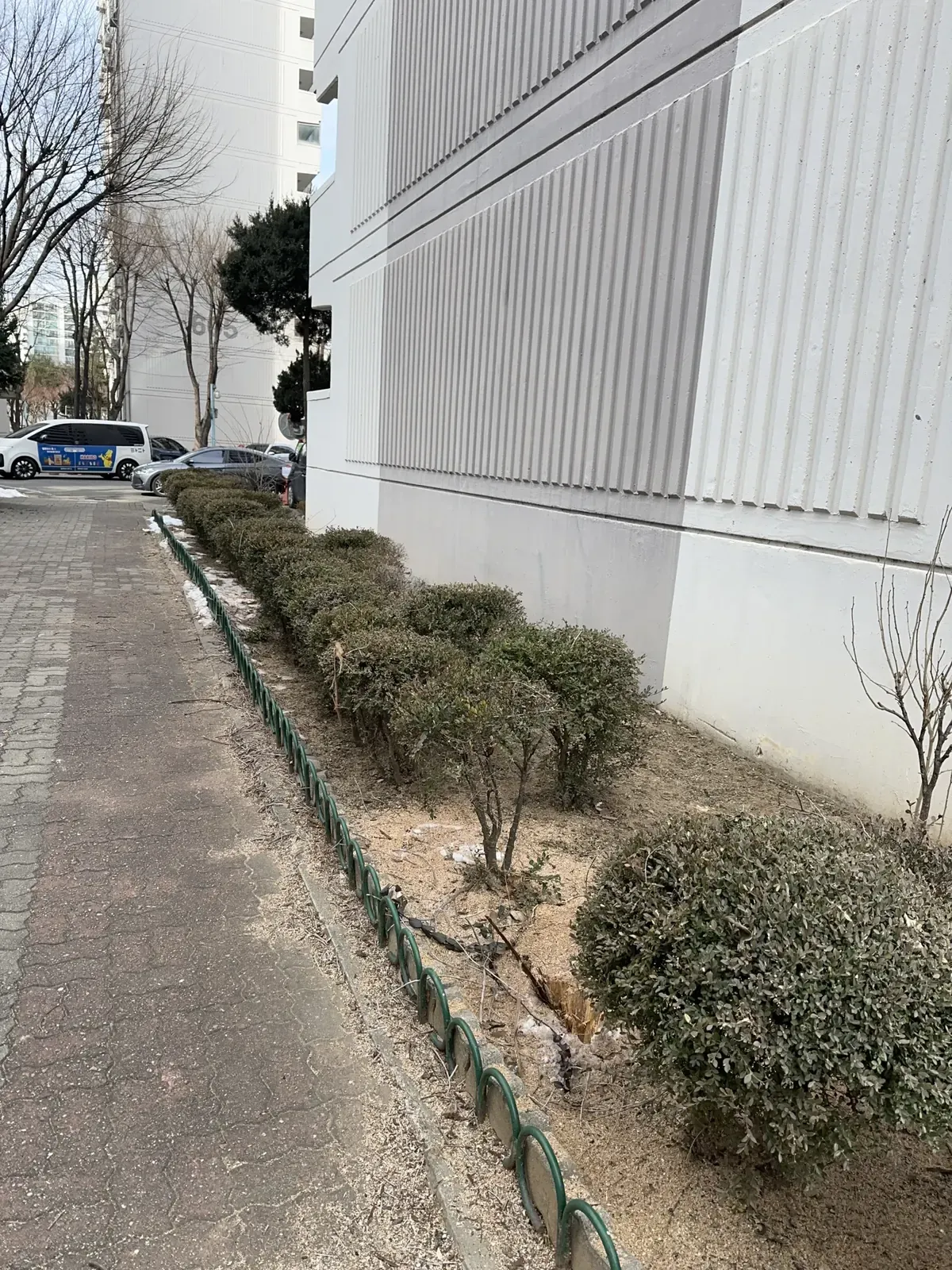 아파트 외벽 옆 보행로와 화단이 이어진 주변 모습